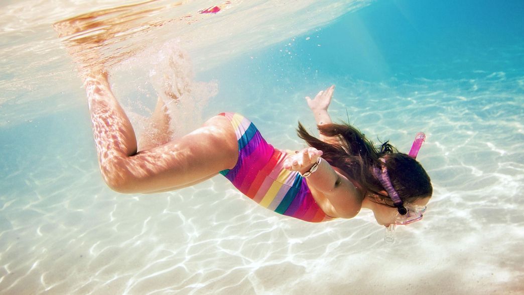 Ein Mädchen in einem farbigen Badeanzug am Tauchen im Meer