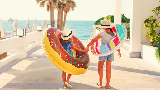 Kinder mit Schwimmring laufend Richtung Meer