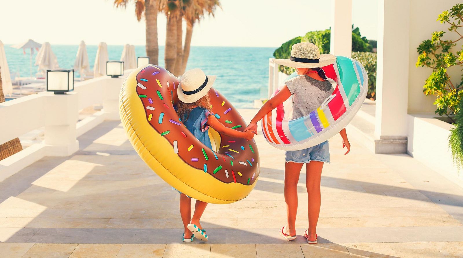 Familienhotel Kinder mit Schwimmring laufend Richtung Meer