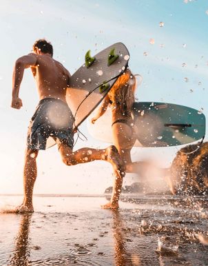 Paar rennt mit Surfbrettern ins Meer