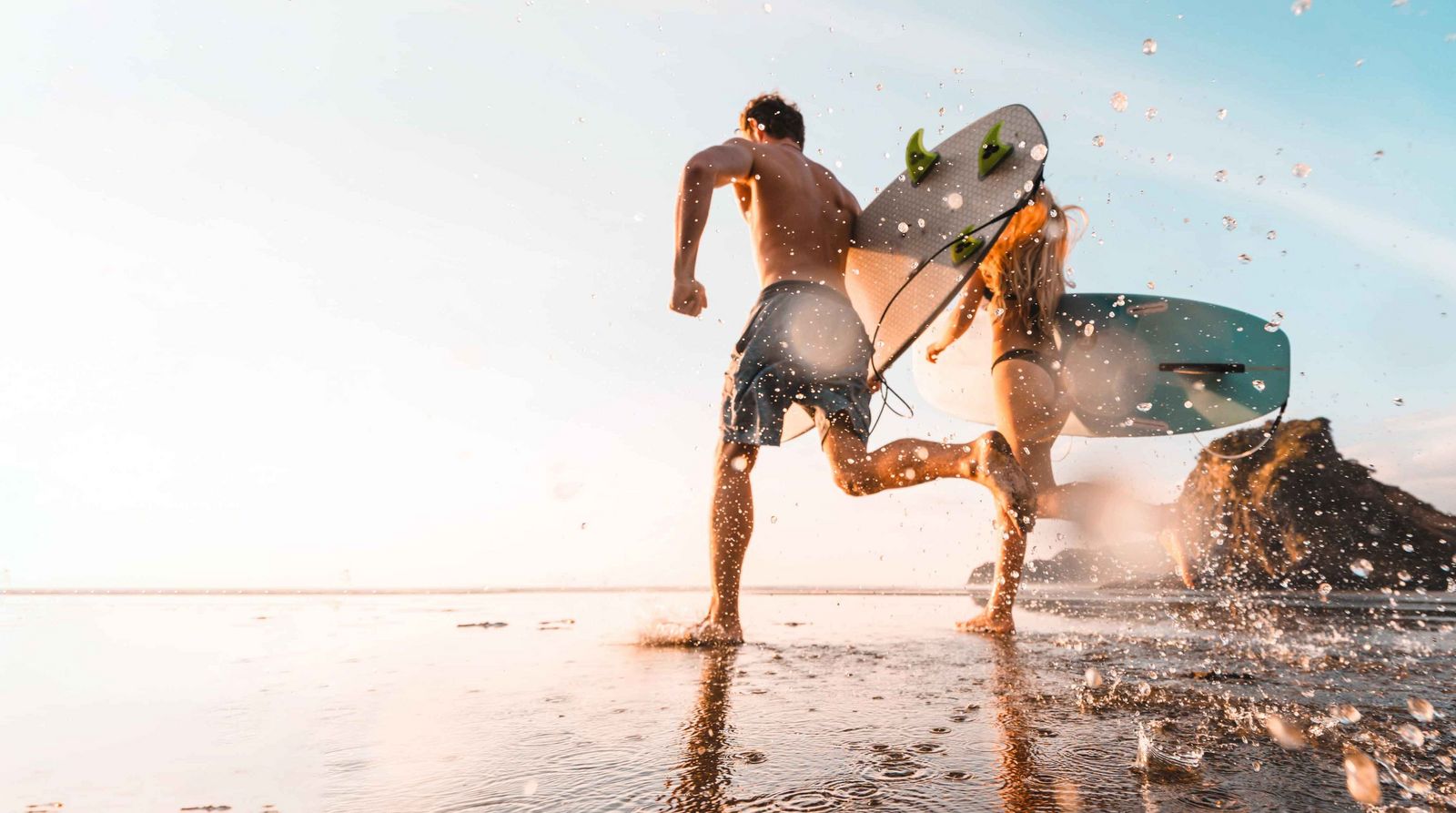 Surfferien Paar rennt mit Surfbrettern ins Meer