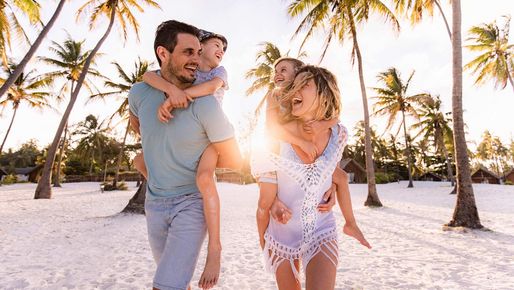 Lachende Familie am Strand unter den Palmen