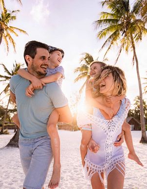 Lachende Familie am Strand unter den Palmen