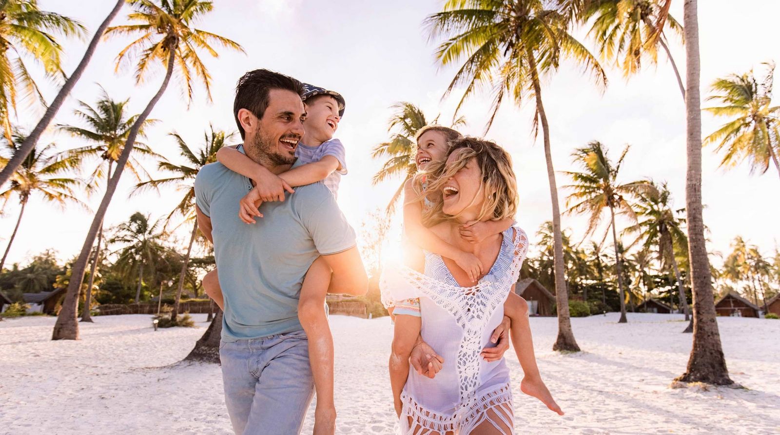 Lachende Familie am Strand unter den Palmen