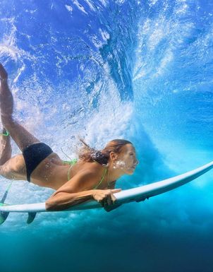 Eine Frau mit Surfbrett unter der Wasseroberfläche