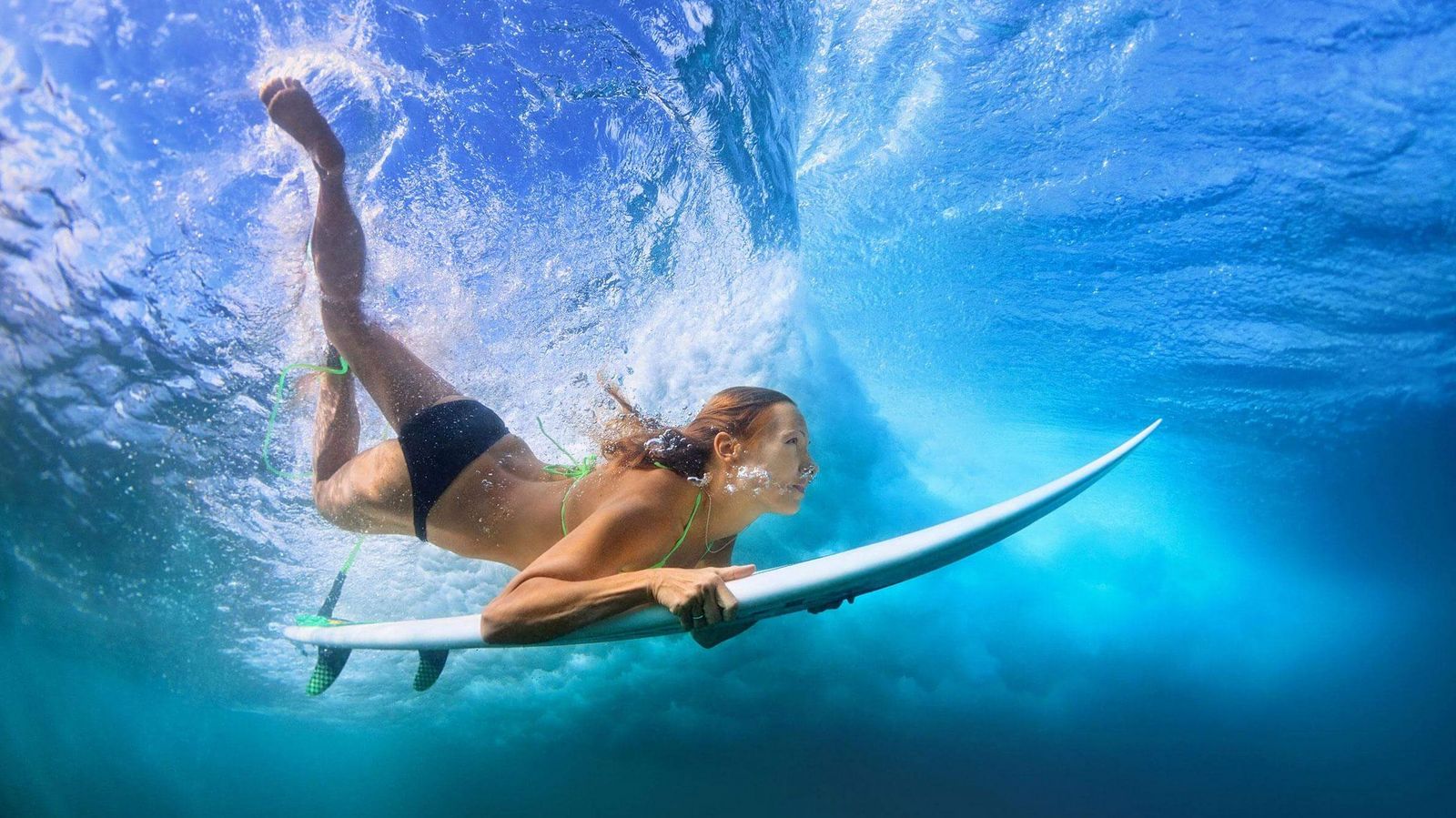 Eine Frau mit Surfbrett unter der Wasseroberfläche