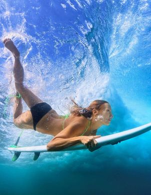 Eine Frau mit Surfbrett unter der Wasseroberfläche