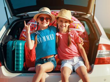 Der Kofferraum ist gepackt und die zwei Schwestern sind bereit für die Ferien