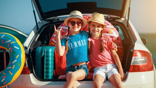 Der Kofferraum ist gepackt und die zwei Schwestern sind bereit für die Ferien