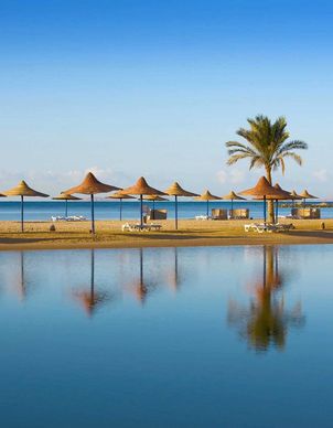 ein Strand mit Palmen und Sonnenschirmen in Hurghada