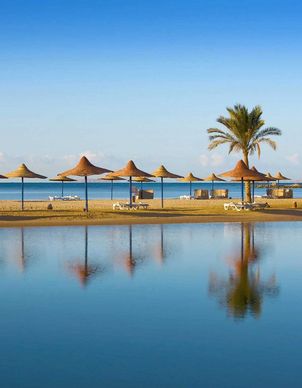 ein Strand mit Palmen und Sonnenschirmen in Hurghada