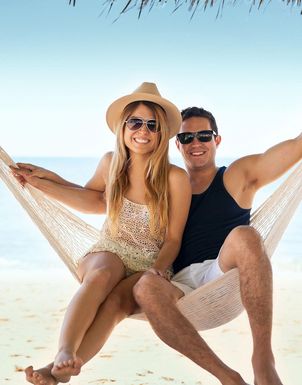 Paar das in einer Hängematte am Strand sitzt