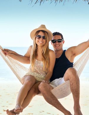 Paar das in einer Hängematte am Strand sitzt