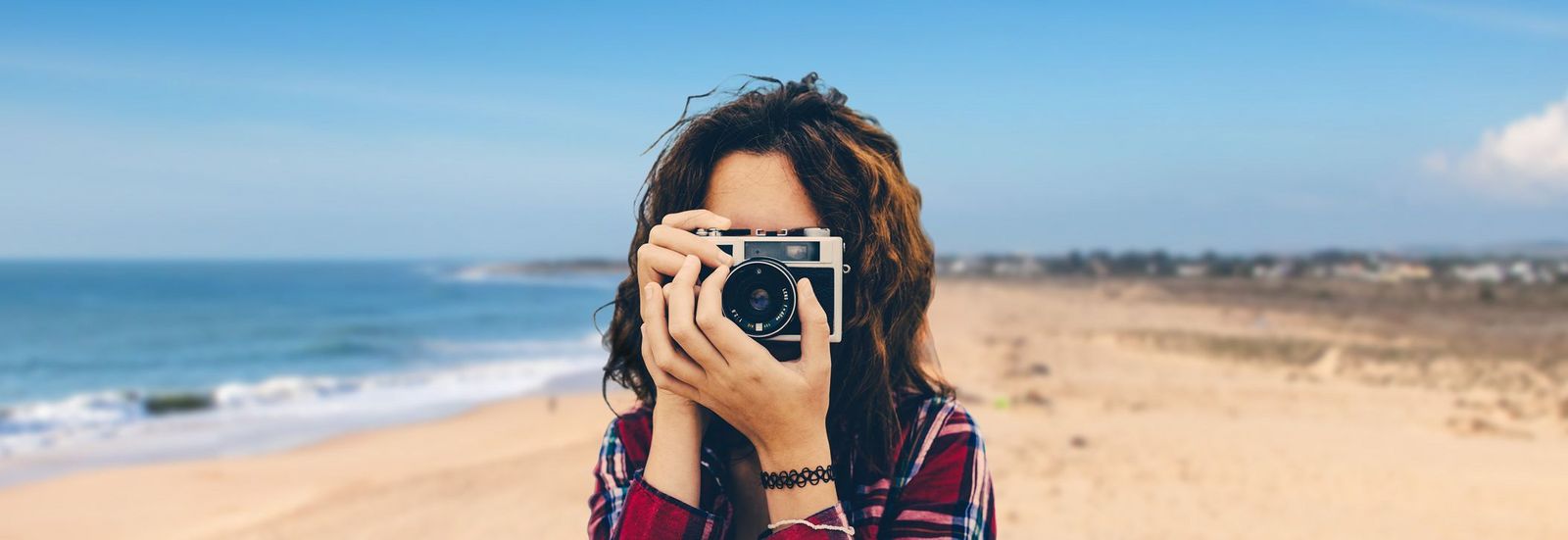 Reiseblog Frau mit Kamera am Strand