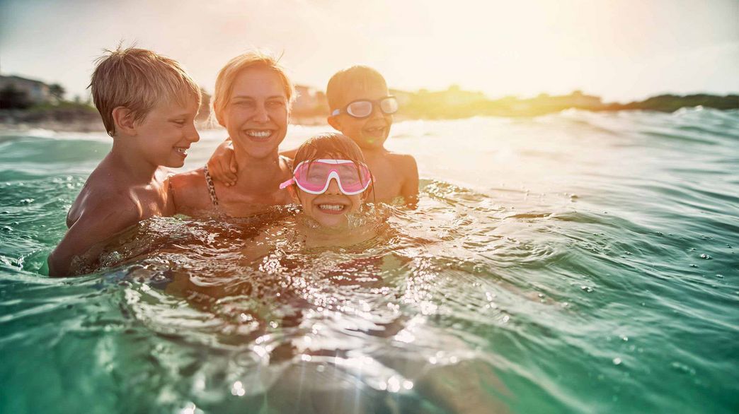Eine Mutter mit drei Kindern am Baden im Meer