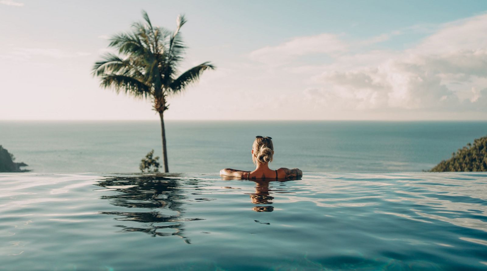Frau geniesst den Blick aufs Meer vom Infinity-Pool