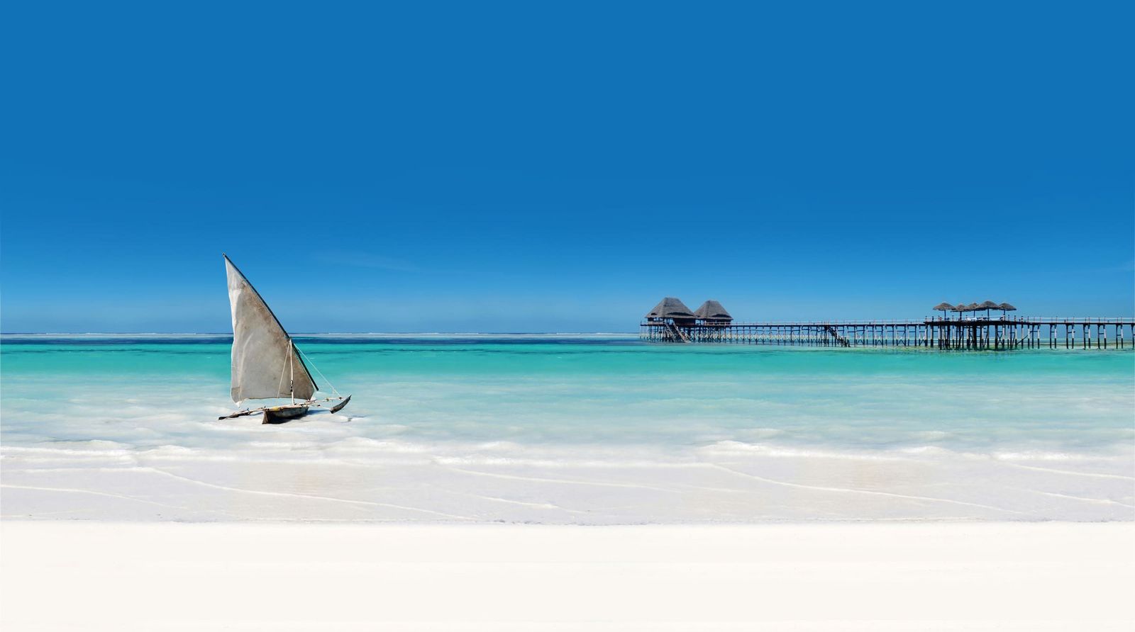 Strand mit einem Steg und einem Fischerboot in Sansibar